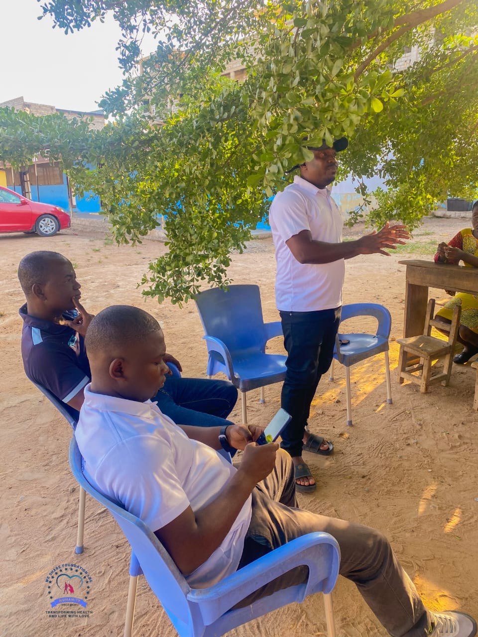 We Share Foundation team briefing volunteers under a tree before a community visit